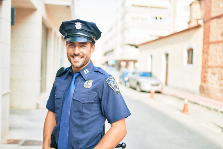 Young handsome hispanic policeman wearing police uniform smiling happy Standing with smile on face at town street