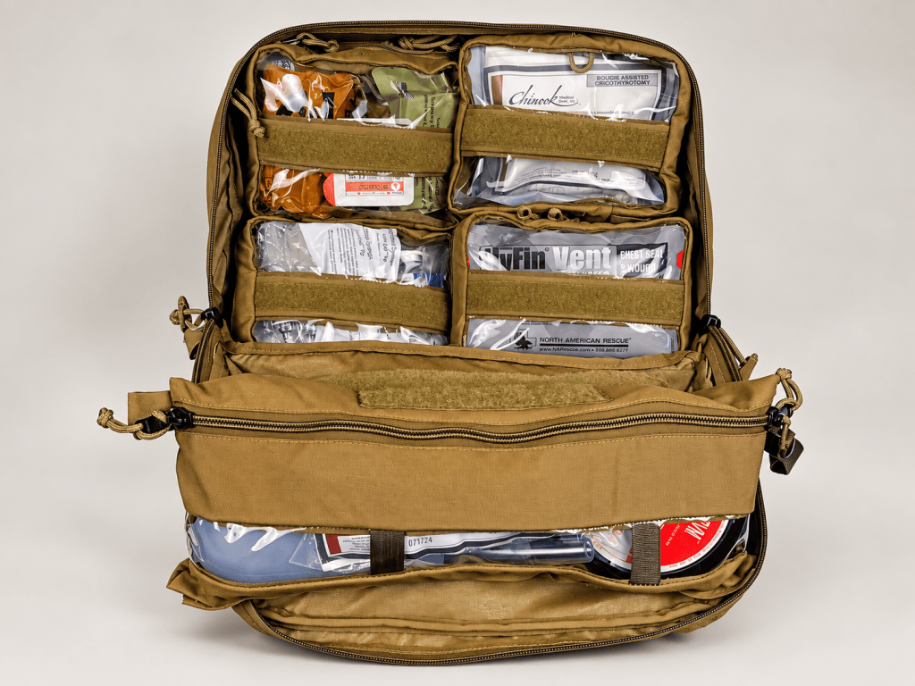 Open tan medical carrier with clear pouches holding grouped supplies.